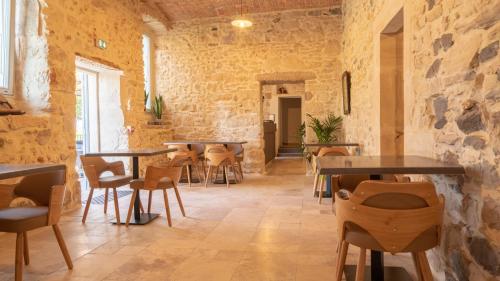 a restaurant with tables and chairs in a stone wall at L'hôtel du Couvent in Vagnas
