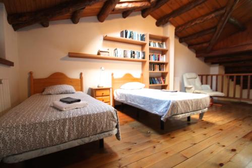 um quarto com duas camas e uma estante de livros em H4, Bordes d'Arinsal, Triplex Rustico con chimenea, Arinsal, Zona vallnord em Mas de Ribafeta