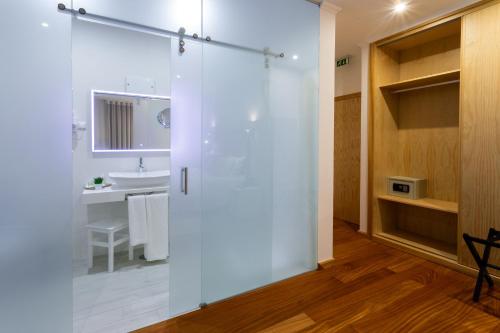 a bathroom with a shower with a sink and a mirror at Quinta da Magnólia AR in Urzelina