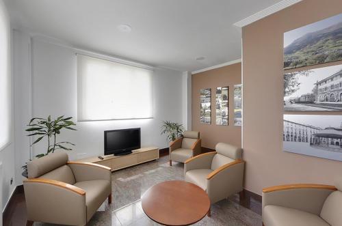 a waiting room with chairs and a tv and a table at Hotel Loiola in Azpeitia