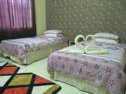 2 Betten in einem Zimmer mit Schwänen darauf in der Unterkunft Kayangan Homestay Perlis a Islamic House in Kangar