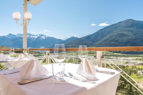 a table with glasses and napkins on a table with mountains at Bio Hotel Panorama in Malles Venosta