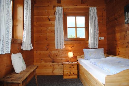 a bedroom in a log cabin with a bed and a window at Ferienwohnungen Anderlbauer in Lofer