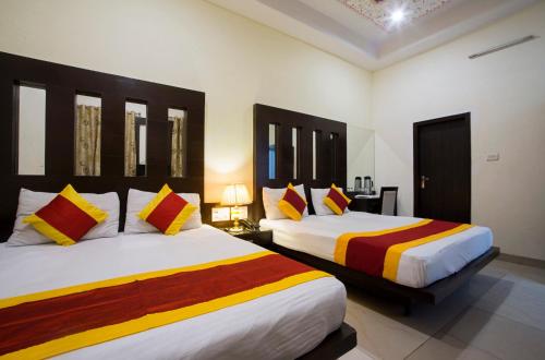 een slaapkamer met 2 bedden en kleurrijke dekens en kussens bij Hotel Baba Inn-By RCG Hotels in New Delhi