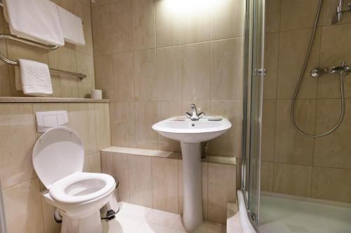 
a white toilet sitting next to a shower in a bathroom at Oktyabrskaya Hotel in Nizhny Novgorod
