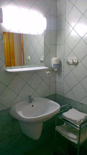 a white bathroom with a sink and a mirror at Lenti Thermal Panzió in Lenti