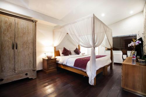 1 dormitorio con cama con dosel y suelo de madera en Villa Margaux, en Seminyak