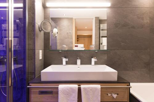 a bathroom with a white sink and a mirror at Alpenhotel Ischglerhof in Ischgl
