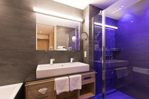 a bathroom with a tub, sink and mirror at Alpenhotel Ischglerhof in Ischgl