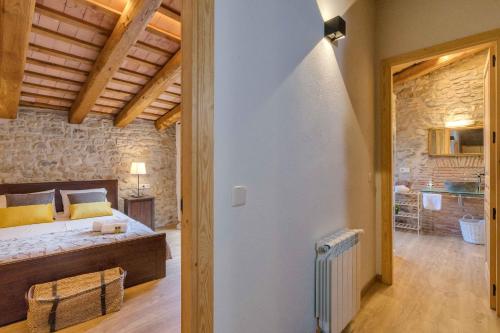 a bedroom with a bed in a room with a stone wall at Flateli Diana in Sant Jordi Desvalls