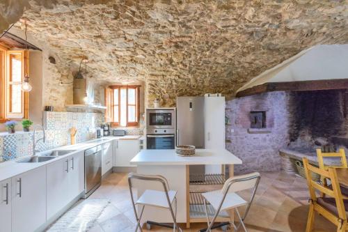 a kitchen with white appliances and a stone wall at Flateli Diana in Sant Jordi Desvalls