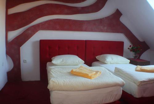 two beds in a room with a red and white ceiling at Arkady in Słupsk
