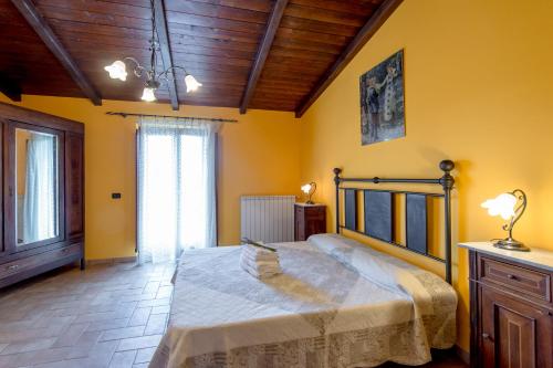 a bedroom with a large bed with yellow walls at Fattoria Capobianco in Montefiascone
