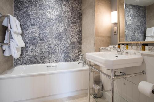 
a white bath tub sitting next to a white sink at The Beverley Arms Hotel in Beverley
