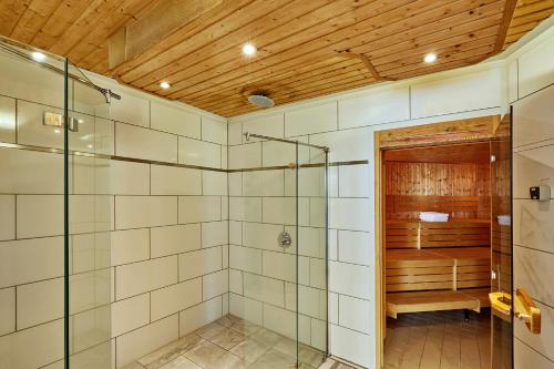 a bathroom with a glass shower and a bench at H+ Hotel Ferienpark Usedom in Ostseebad Koserow