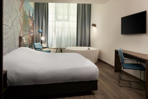 a hotel room with a bed and a desk and a tub at Inntel Hotels Amsterdam Centre in Amsterdam