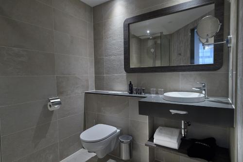 a bathroom with a toilet and a sink and a mirror at Inntel Hotels Amsterdam Centre in Amsterdam