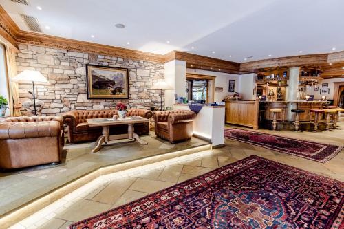 a living room with leather furniture and a stone wall at Sporthotel Kirchler in Tux