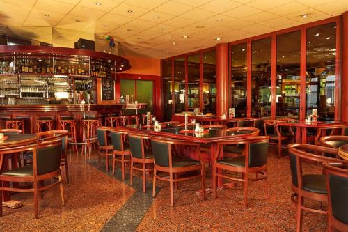 a restaurant with wooden tables and chairs and a bar at H+ Hotel Hannover in Hannover