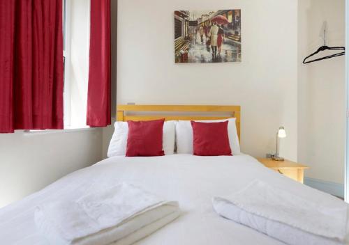 a bedroom with a white bed with red pillows at Southsea Rocks Hotel in Portsmouth