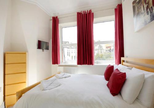 a bedroom with a large bed with red curtains at Southsea Rocks Hotel in Portsmouth