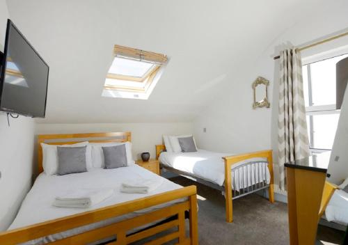 a bedroom with two beds and a tv and a window at Southsea Rocks Hotel in Portsmouth