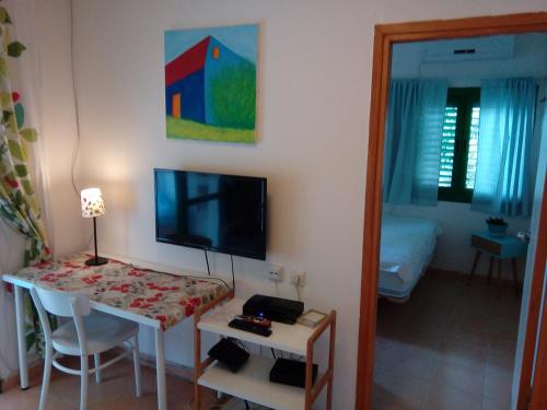 a room with a table and a television and a room with a bed at Tal Shahar room in Tal Shaẖar