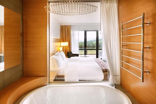 a large bath tub in a room with a bedroom at Radisson Blu Resort Bukovel in Bukovel