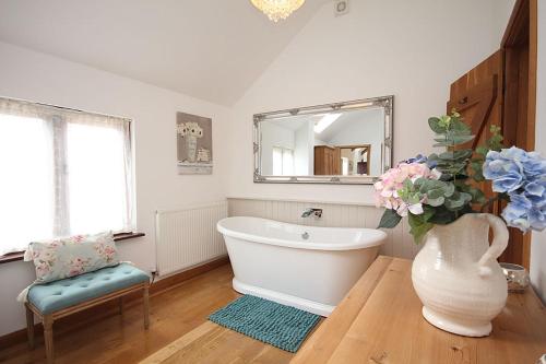 a bathroom with a white tub and a vase with flowers at The Old Stables in Taunton