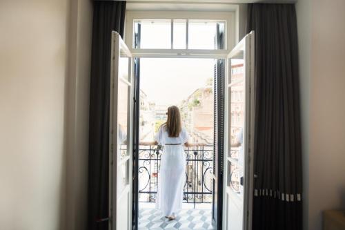 a woman in a white dress standing on a balcony at Antigon Urban Chic Hotel, Thessaloniki in Thessaloniki