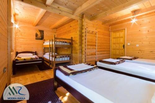 a room with three beds in a wooden cabin at Rafting Camp Modra Rijeka in Šćepan-Polje