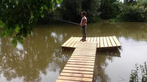 a boy standing on a dock holding a fishing pole at Vass-Villa Vendégház in Szekszárd