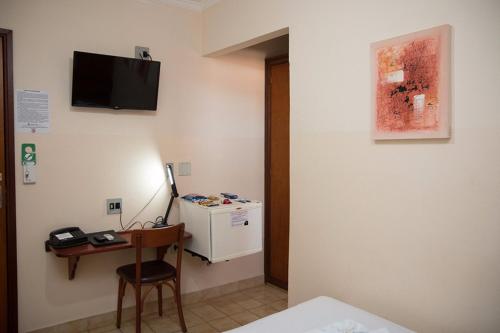 a room with a desk and a television on the wall at Hotel São Marcos in Orlândia