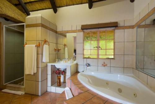 a large bathroom with a tub and a sink at Lions Rock Rapids - Lodge in Hazyview