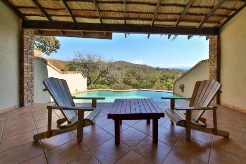 a patio with a table and two chairs and a pool at Lions Rock Rapids - Lodge in Hazyview