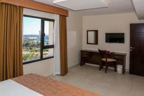 um quarto de hotel com uma secretária e uma janela em City Tower Hotel em Aqaba