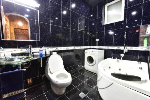 a black tiled bathroom with a toilet and a sink at Tbilisi Art Apartment in Tbilisi City
