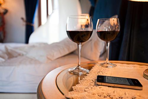 two glasses of red wine on a table with a cell phone at Albergo La Lanterna in Sarteano