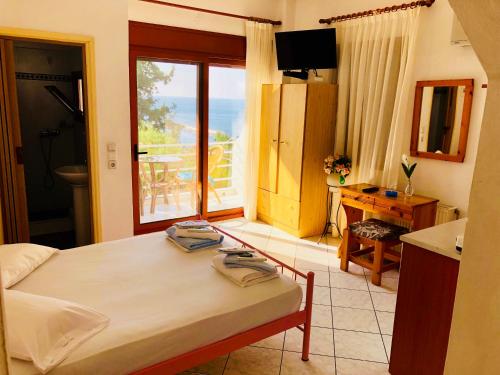 a bedroom with a bed and a table and a window at Rooms Olympia in Gialiskari