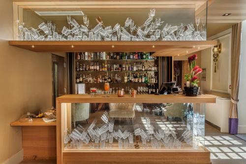 a display case in a bar with glasses at La Cour des Consuls Hotel & Spa Toulouse - MGallery Collection in Toulouse