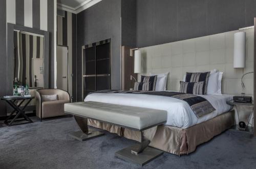 a bedroom with a large bed and a chair at La Cour des Consuls Hotel & Spa Toulouse - MGallery Collection in Toulouse