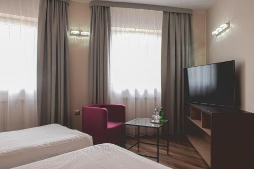 a hotel room with a tv and a bed and a chair at Hotel Major Budget in Kraków