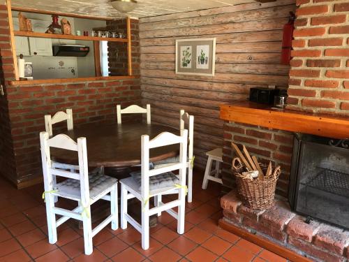 comedor con mesa y sillas junto a una chimenea en Cabaña frente al lago en San Martín de los Andes
