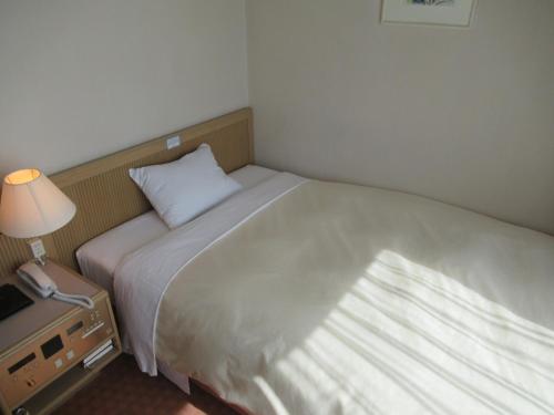 a bedroom with a bed and a lamp and a window at Hotel Grand Terrace Chitose in Chitose