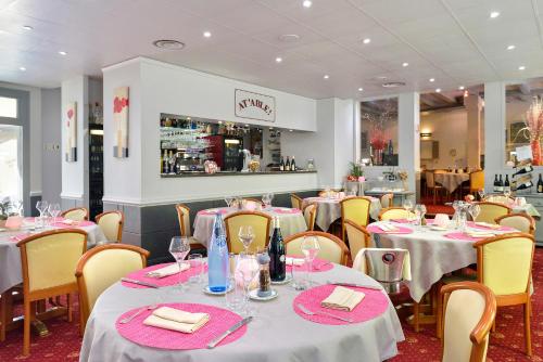 un ristorante con tavoli e sedie con tovaglie bianche di Logis Hôtel Restaurant La Boule d'Or a Chinon
