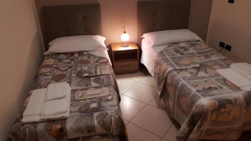 1 dormitorio con 2 camas y mesita de noche con lámpara en Casa Vacanza "La Chiazza di Grutti", en Grotte