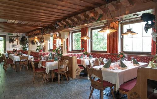 un restaurant avec des tables blanches, des chaises et des fenêtres dans l'établissement Gasthof Jägerklause, à Stummerberg