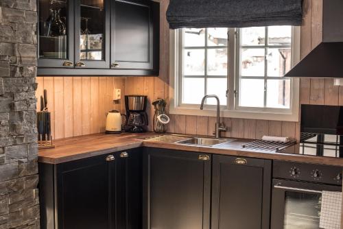 a kitchen with black cabinets and a sink at Vågåvatnet Feriesenter in Vågåmo