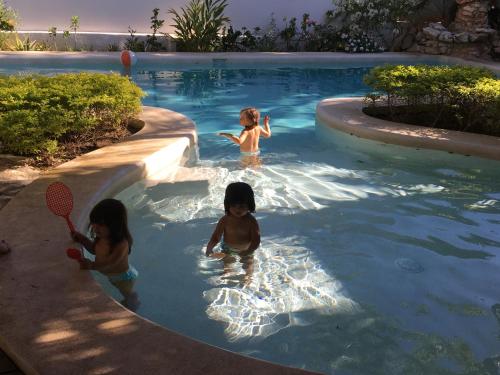 three children are playing in a swimming pool at Villa Maria Bed and Breakfast in Puerto Escondido