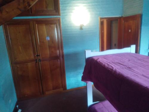 a bedroom with a bed and a cabinet with a purple blanket at Universal Traveller's Hostel in San Carlos de Bariloche